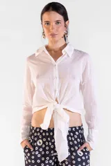 Camisa de manga larga color blanco crema, confeccionada en 100% algodón, con cuello camisero, botones nacarados y diseño con largo para anudar al frente.