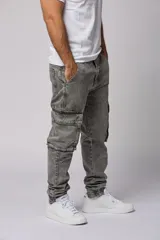 Pantalón jean gris claro, estilo jogger, con bolsillos cargo laterales y puños elásticos en los tobillos.