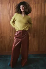 Pantalón de tiro medio confeccionado en 100% piel, con diseño de pierna ancha, cintura con trabillas, bolsillos laterales y cierre frontal con cremallera, botón y ganchos metálicos.