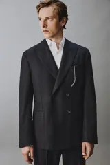 Blazer de corte regular fit confeccionado en lana italiana, con diseño de raya diplomática. Presenta cuello con solapas de pico, cierre frontal de botonadura cruzada, bolsillos de vivo en el pecho y bolsillos de solapa en la cadera.