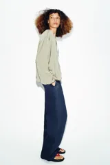 Cazadora bomber fluida de color verde, con cuello redondo, manga larga abullonada, bolsillos frontales y cierre de cremallera metálica.