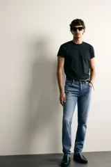 Jeans slim fit de color negro para hombre, con tiro medio, diseño de cinco bolsillos y cierre frontal con cremallera y botón.