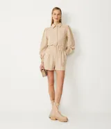 Short tipo clochard de tiro alto confeccionado en tejido tweed con estampado cuadrillé en tonos beige y crema. Presenta cintura elástica, bolsillos laterales y detalle de botones metalizados frontales.