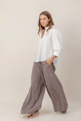 Pantalón de corte ancho y tiro alto, color gris topo, confeccionado en tencel con detalle de pequeñas aplicaciones de strass distribuidas por toda la prenda.