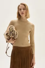 Polera de tejido de punto acanalado en color beige, con cuello alto y mangas largas. Presenta un sutil acabado brillante gracias a sus detalles en lurex.