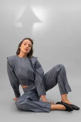 Campera corta de lana y seda color gris con cierre frontal oculto y mangas largas con diseño de tablas en los puños.