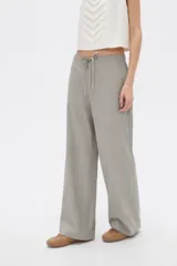 Pantalón de algodón color gris, de tiro medio y corte holgado tipo baggy, con bolsillos laterales y cordón ajustable en la cintura.