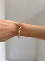 Pulsera elástica compuesta por cuentas de cristal facetado en diversos colores y tonos pasteles, con un dije central en forma de mariposa de material traslúcido.