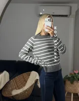 Sweater de punto con diseño de rayas horizontales negras sobre fondo blanco, cuello redondo y puños y ruedo acanalados.