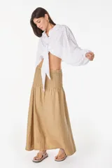 Top blanco de manga larga con diseño abullonado, cuello camisero, cierre frontal con botones y nudo ajustable en la cintura. Con textura sutil en la tela.