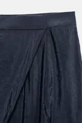 Pantalón de tiro alto con diseño cruzado tipo pareo en el frente, pernera ancha y caída fluida.