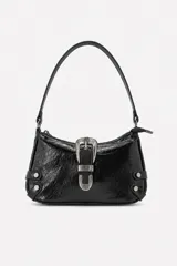 Bolso de PU negro con textura craquelada, asa corta para hombro y cierre superior. Presenta una hebilla decorativa plateada de estilo western en el frente y detalles de tachas metálicas en los laterales.