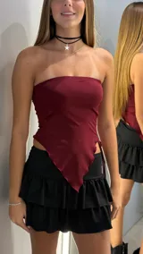 Top strapless color bordó, con diseño asimétrico en la parte inferior y fruncido lateral con cordones ajustables.