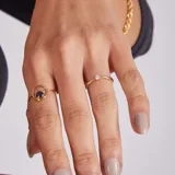 Anillo de oro 18k con diseño minimalista que presenta un zafiro azul engastado en un círculo metálico.