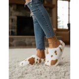 Pantuflas sin talón confeccionadas en algodón afelpado y piel sintética, con divertido estampado de manchas de vaca en tonos blanco y marrón, y suela de PVC.