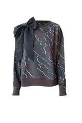 Buzo negro con estampado de líneas blancas y lazo decorativo en el hombro.