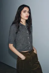 Chaqueta de punto con textura cepillada, cuello polo y manga corta. Presenta cierre frontal con botones y diseño de corte recto.