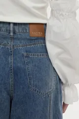Pantalón jean de pierna ancha con calce relajado y detalles de costuras decorativas verticales en el frente, color azul.