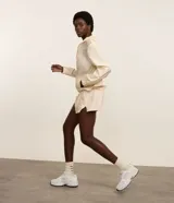 Campera rompevientos deportiva de mujer, marca Get Over, color beige con sutiles rayas verticales, cuello alto, cierre frontal con cremallera y puños ajustados.