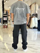 Remera oversize gris con efecto acid wash, de mangas cortas y cuello redondo, con estampado tipográfico blanco en la espalda.