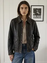 Chaqueta de cuero vacuno con acabado envejecido, diseño de cuello camisero, cierre frontal con botones metálicos y bolsillos frontales con solapa.