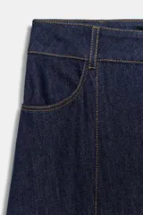 Falda midi de denim en color azul oscuro, con diseño evasé, bolsillos delanteros, costuras pespuntadas en contraste y cierre frontal con cremallera y botón metálico.