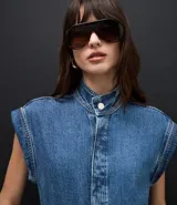 Mono utilitario de jean color azul medio, con cuello mao, cierre frontal oculto, diseño sin mangas con hombreras estructuradas, cintura entallada con trabillas y bolsillos funcionales.