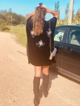 Vestido corto negro de terciopelo con bordado de flores blancas en la espalda, escote en V y corte holgado.