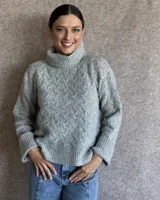 Sweater de lana color crudo con cuello alto y diseño trenzado.