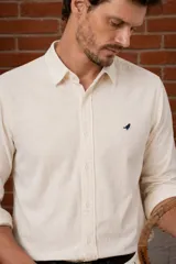 Camisa de pana color beige, con corte slim fit, cuello corto, mangas largas y pequeño bordado de un ave en el pecho.