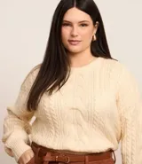 Suéter de punto pesado color crema, con cuello redondo y mangas largas. Presenta textura trenzada.