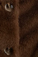 Campera de textura suave efecto peluche, color marrón, con cuello redondo, cierre frontal con botones y forro interior.