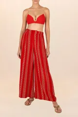 Pantalón de corte recto color rojo con estampado de cadenas doradas, pretina elástica, cierre y broche al frente, pinzas y bolsillos laterales.