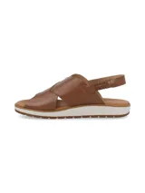 Sandalia de cuero color camel con tiras cruzadas en el empeine y tira trasera con elástico. Cuenta con una suela plana de goma con detalle de franja blanca y base dentada.