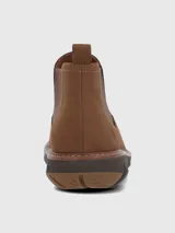Bota tipo Chelsea de cuero color marrón, con paneles elásticos laterales y suela tecnológica Spinal Flex de color marrón oscuro que ofrece amortiguación y soporte.