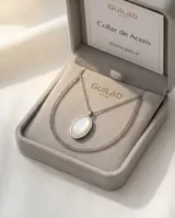 Collar de cadena fina de acero con dije ovalado de nácar engarzado en metal plateado.