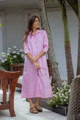 Vestido camisero midi color rosa claro, con cuello camisero, mangas 3/4 y cierre frontal con botones.