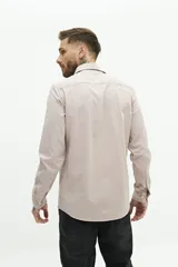Camisa de manga larga lisa con cuello clásico y cierre frontal de botones. Presenta un ajuste regular y un pequeño logo bordado en el pecho.