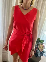 Conjunto de dos piezas color rojo, compuesto por un top sin mangas con escote en V y una falda corta cruzada con lazo ajustable a la cintura.