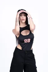 Body negro con recorte en el pecho y estampado del número 28 en rosa. Short negro de jean con bolsillos.