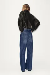 Chaqueta estilo bomber de efecto piel en color marrón oscuro, con cuello solapa, cierre frontal con cremallera, bolsillos delanteros de vivo y bajo acabado en elástico.