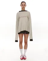 Sweater tejido color crema con bordado manual en forma de zig-zag color naranja. Terminaciones de cuello y puños en color marrón.