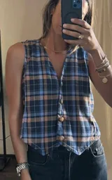 Chaleco de corte sastrero con escote en V y cierre frontal de botones. Presenta un diseño de estampado a cuadros en tonos azul y marrón.