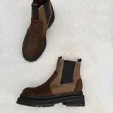 Botas estilo Chelsea de cuero color marrón, con paneles elásticos laterales negros, presillas traseras y suela chunky de goma negra con plataforma dentada.