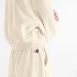Short New Balance de felpa francesa color beige, con cintura elástica y cordón de ajuste. Cuenta con bolsillos laterales y detalle de bordado y estampado con el logo de la marca en el muslo izquierdo.