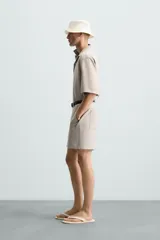 Bermuda de algodón color blanco, de corte relajado, con cintura elástica, bolsillos frontales y bolsillos traseros de plastrón. Cierre frontal con cremallera y botón.