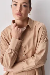 Camisa celeste de corte oversize, con mangas largas, cuello camisero y cierre frontal de botones.