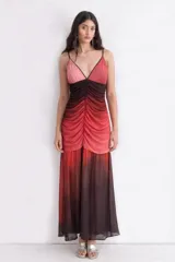 Vestido largo con breteles finos y escote en V, con diseño degradado en tonos rojizos y oscuros. Presenta un frunce central en el torso que realza la silueta y una falda amplia con caída liviana.