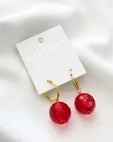 Aros colgantes con aro dorado y dije de cristal facetado color rojo. Marca Valente Accesorios.