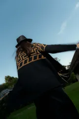 Saco tejido de punto con diseño de guarda inca en la parte superior. Presenta bolsillos frontales con detalles de tiras de cuero y flecos. De corte recto y largo medio, con terminaciones en tejido acanalado.